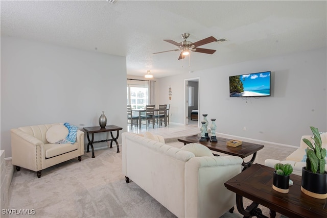 carpeted living room featuring ceiling fan and a textured ceiling