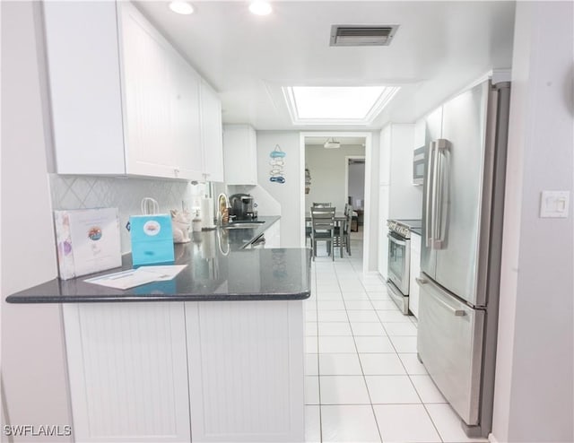 kitchen with kitchen peninsula, white cabinetry, light tile patterned floors, and appliances with stainless steel finishes