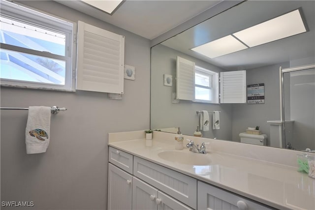 bathroom with vanity, a shower with shower door, and toilet