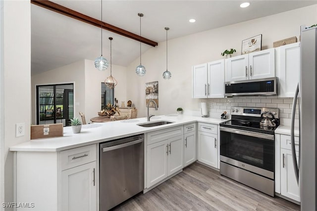 kitchen featuring decorative backsplash, kitchen peninsula, stainless steel appliances, sink, and hanging light fixtures