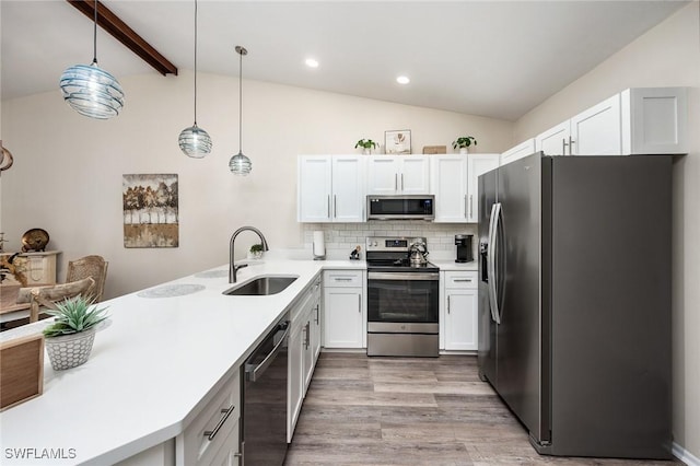 kitchen with backsplash, white cabinetry, hanging light fixtures, and stainless steel appliances