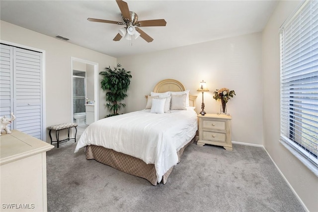 bedroom with ensuite bathroom, light colored carpet, ceiling fan, multiple windows, and a closet