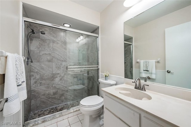 bathroom with tile patterned flooring, vanity, a shower with shower door, and toilet