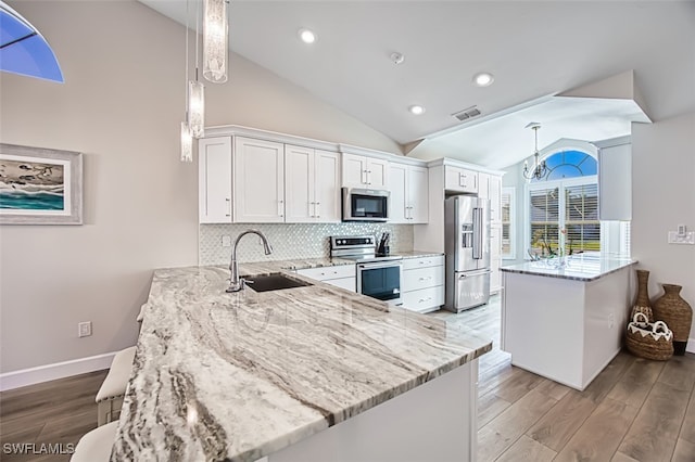 kitchen with kitchen peninsula, sink, white cabinets, and stainless steel appliances