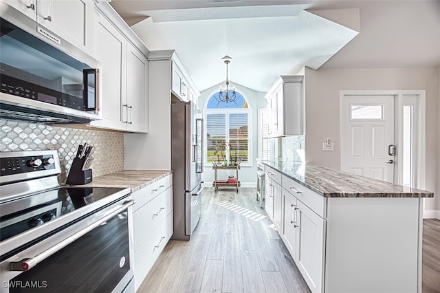 kitchen with a chandelier, appliances with stainless steel finishes, white cabinetry, and light stone counters