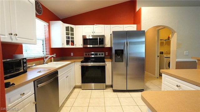 kitchen featuring lofted ceiling, white cabinets, sink, appliances with stainless steel finishes, and light tile patterned flooring