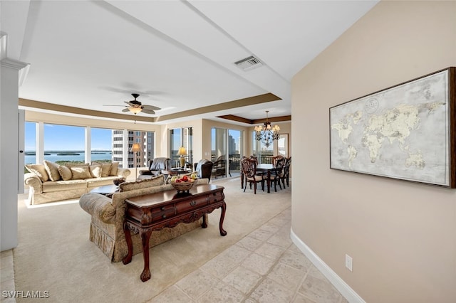 carpeted living room with ceiling fan with notable chandelier and a water view