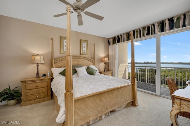 bedroom with access to outside, ceiling fan, light colored carpet, and a water view