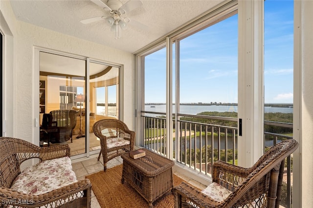 sunroom featuring ceiling fan and a water view