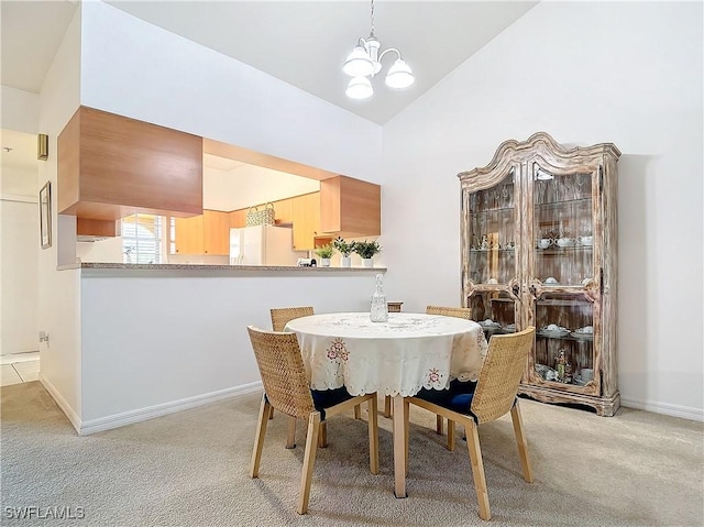 dining space featuring a chandelier, light colored carpet, and high vaulted ceiling