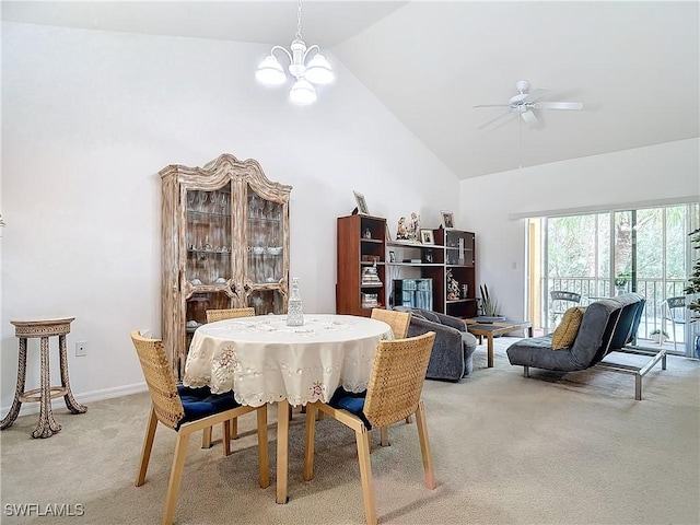 carpeted dining area with ceiling fan with notable chandelier and high vaulted ceiling