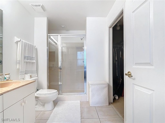 bathroom with tile patterned flooring, vanity, toilet, and walk in shower