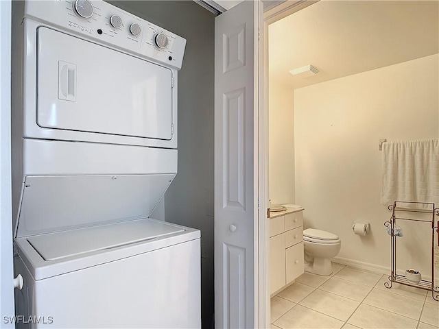 laundry room with stacked washer / dryer and light tile patterned floors