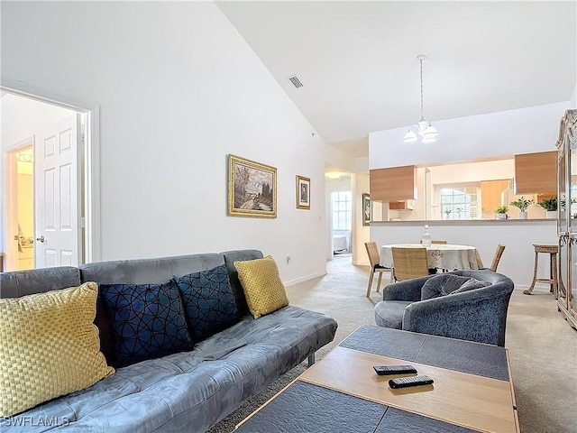 living room featuring a notable chandelier, light carpet, and high vaulted ceiling