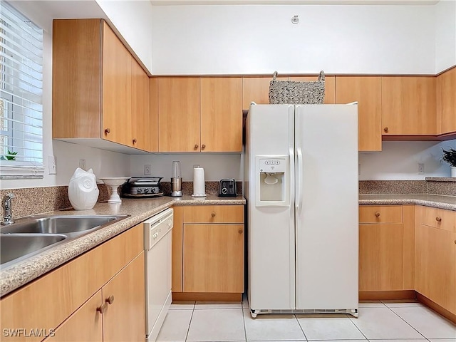 kitchen with light brown cabinetry, sink, light tile patterned floors, and white appliances