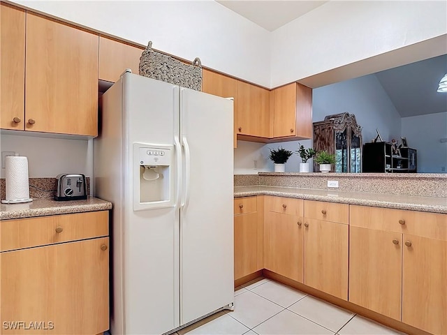 kitchen with light brown cabinetry, light tile patterned floors, and white refrigerator with ice dispenser