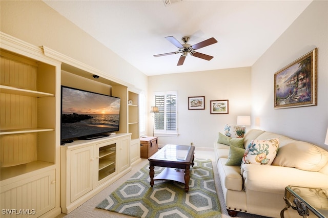 carpeted living room with built in shelves and ceiling fan