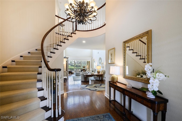 entryway featuring a notable chandelier, a towering ceiling, and dark wood-type flooring