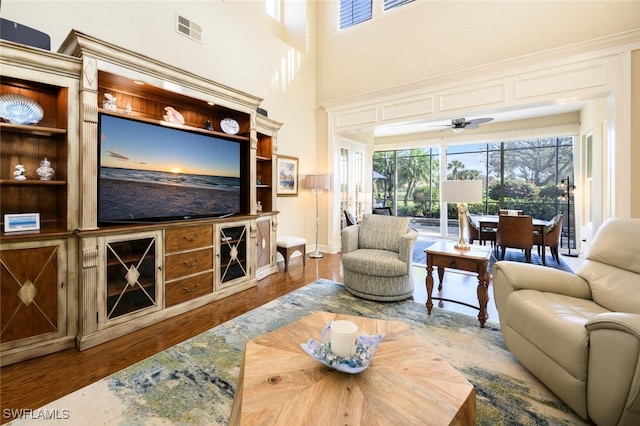 living room with wood-type flooring, ceiling fan, and built in shelves