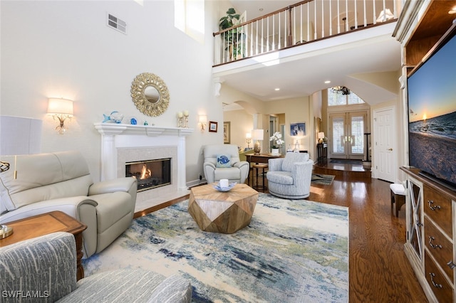 living room featuring dark hardwood / wood-style flooring, french doors, a tile fireplace, and a high ceiling