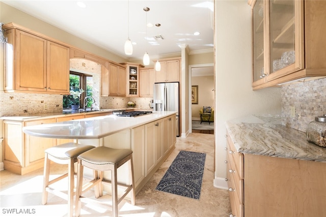 kitchen with light brown cabinetry, backsplash, appliances with stainless steel finishes, sink, and a kitchen island