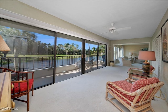 sunroom / solarium featuring ceiling fan and a water view