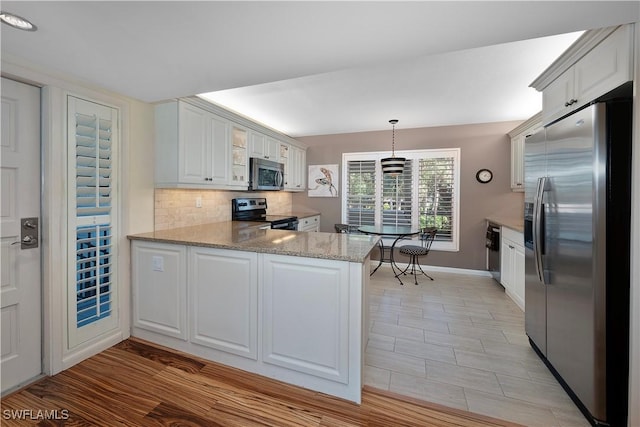 kitchen with stainless steel appliances, backsplash, kitchen peninsula, pendant lighting, and white cabinets