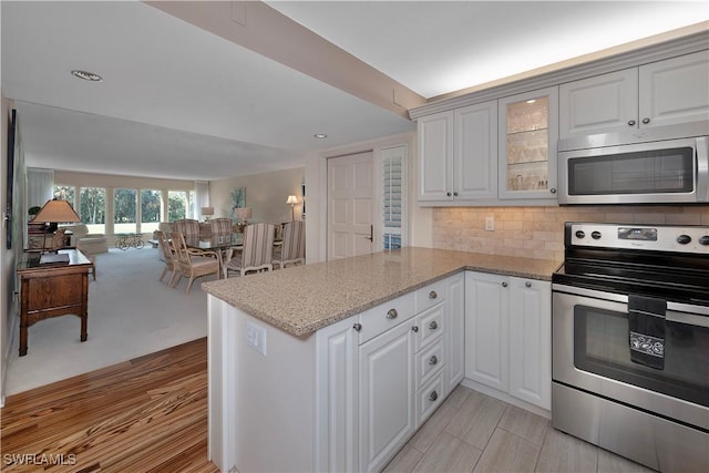 kitchen with kitchen peninsula, appliances with stainless steel finishes, and white cabinetry