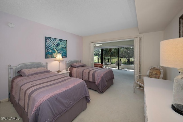 bedroom with a textured ceiling, access to outside, and light colored carpet