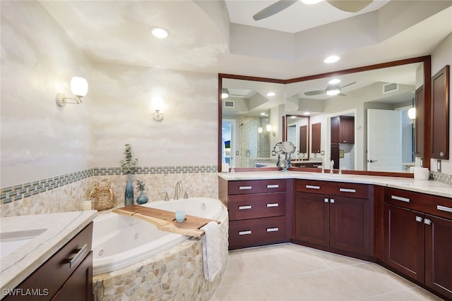 bathroom featuring tiled bath, vanity, a tray ceiling, and tile patterned floors