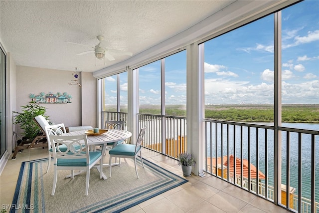 sunroom / solarium with ceiling fan and a water view