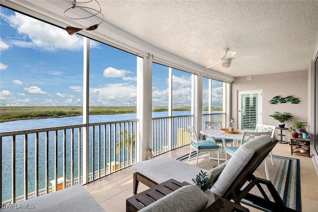 sunroom / solarium featuring a water view, plenty of natural light, and ceiling fan