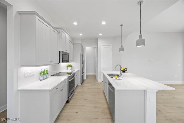 kitchen featuring decorative backsplash, appliances with stainless steel finishes, a kitchen island with sink, sink, and pendant lighting