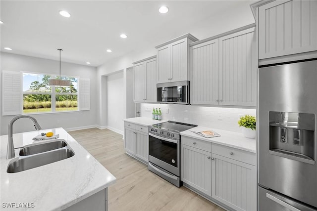 kitchen featuring backsplash, gray cabinetry, stainless steel appliances, sink, and pendant lighting