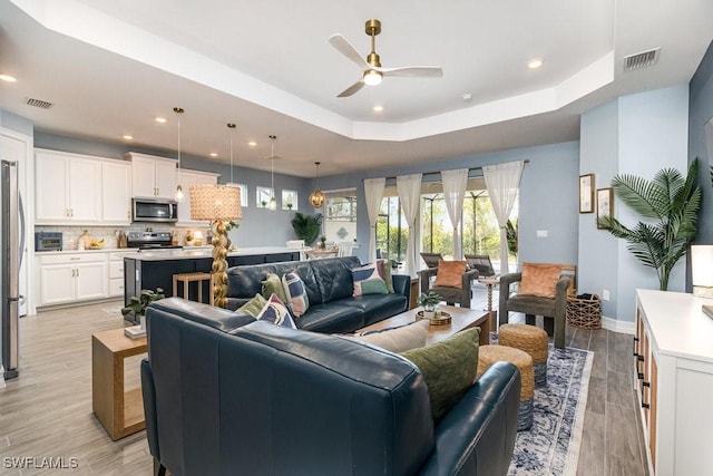 living room featuring a tray ceiling and ceiling fan