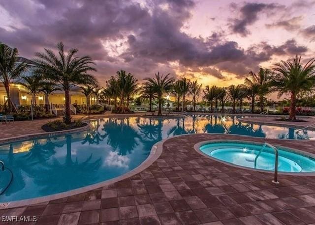 pool at dusk featuring a community hot tub