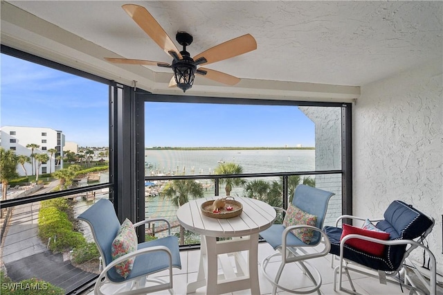 sunroom / solarium with a water view and ceiling fan