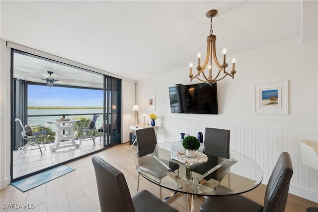 dining area with ceiling fan with notable chandelier and expansive windows