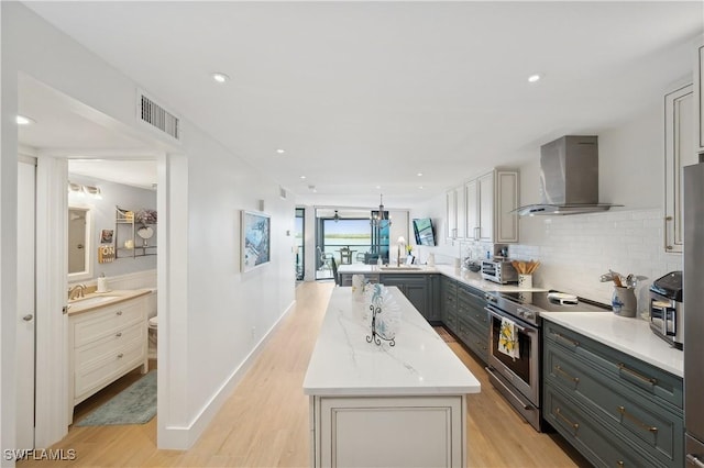 kitchen with wall chimney exhaust hood, tasteful backsplash, light hardwood / wood-style flooring, kitchen peninsula, and electric stove