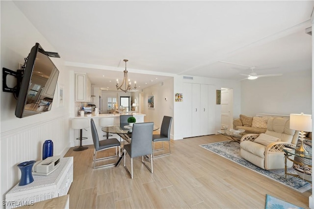 dining space with ceiling fan with notable chandelier and light wood-type flooring