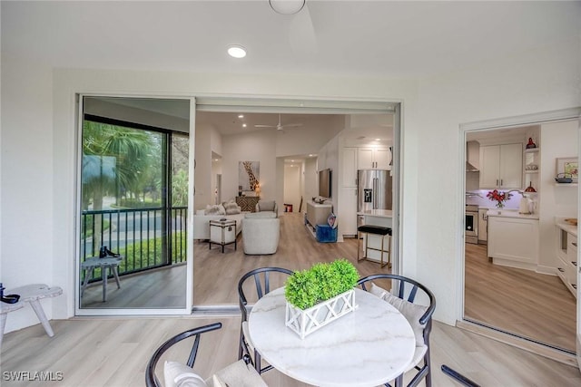 dining area with light wood-type flooring and ceiling fan