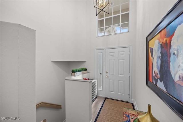 entryway featuring hardwood / wood-style flooring, a high ceiling, and a chandelier