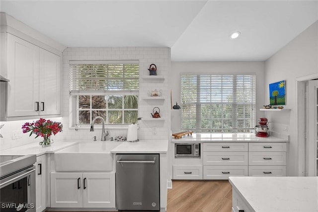 kitchen with decorative backsplash, sink, white cabinetry, and stainless steel appliances