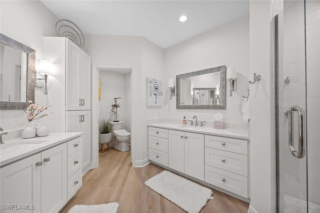 bathroom with toilet, vanity, an enclosed shower, and hardwood / wood-style flooring