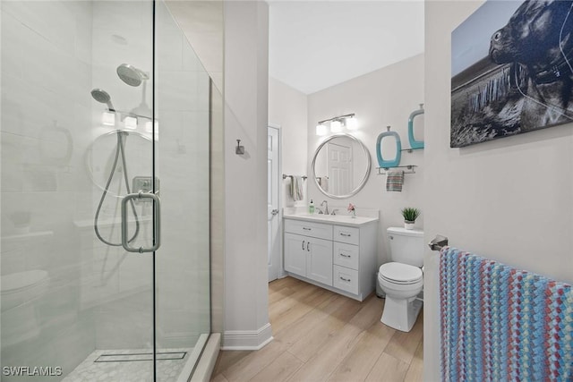 bathroom with an enclosed shower, vanity, toilet, and wood-type flooring