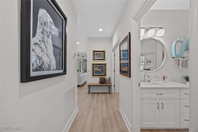 hall with light wood-type flooring and sink