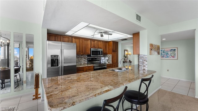 kitchen with a breakfast bar, sink, tasteful backsplash, appliances with stainless steel finishes, and kitchen peninsula