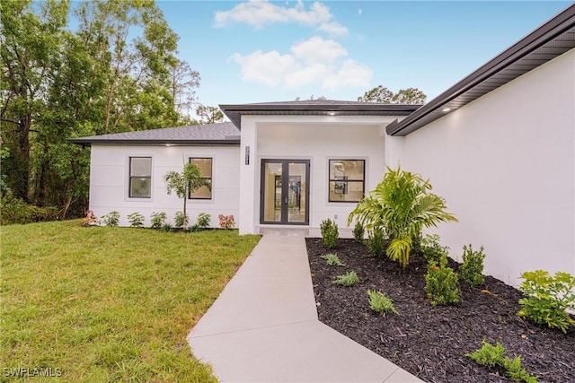 view of exterior entry with french doors and a yard