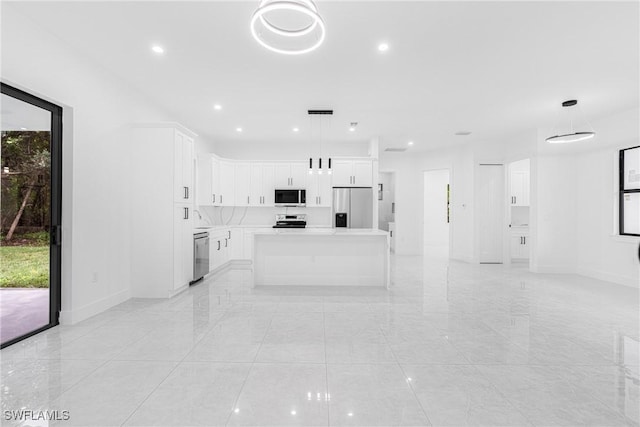 kitchen with decorative light fixtures, white cabinets, appliances with stainless steel finishes, and a kitchen island