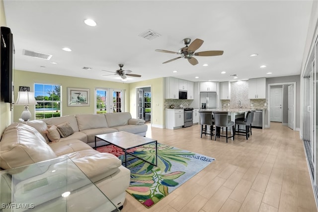 living room featuring french doors, light hardwood / wood-style flooring, ceiling fan, and sink